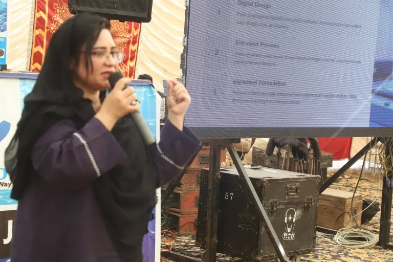 Researcher presenting her paper beside the LED screen at GSTMC-25 in Jhang