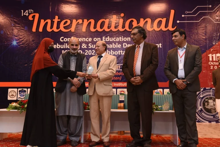 Shield being presented to a student participant on the ICEPSD-25 stage in Abbottabad