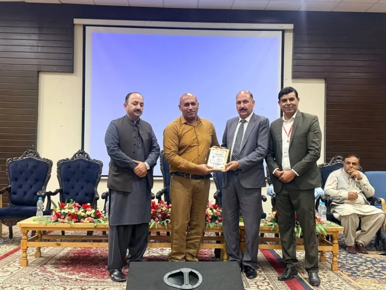 Shield presented to a researcher on stage at ICFAS-26, Karakoram International University, Gilgit